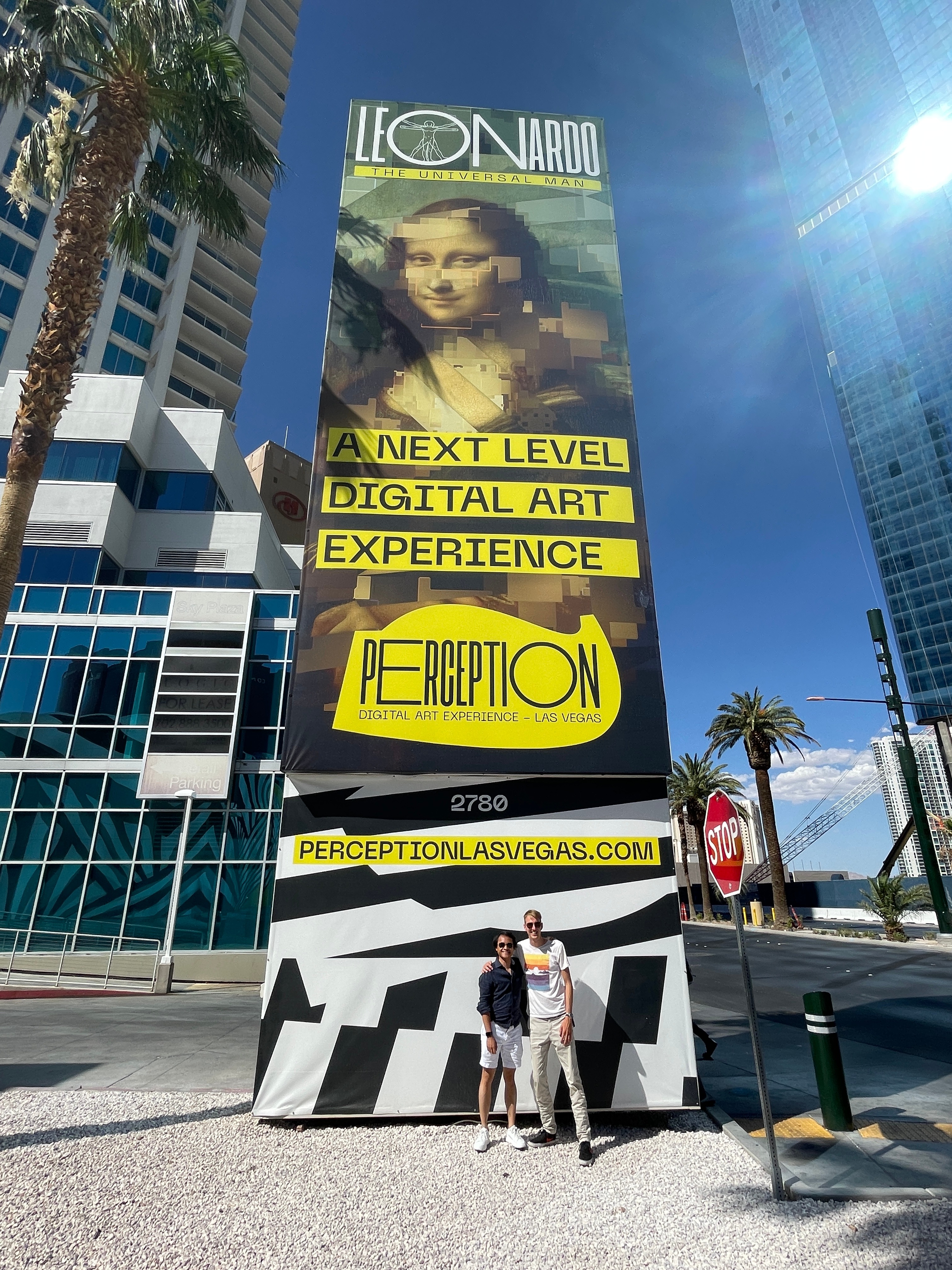 Two people in front of a Perception digital art experience banner in Las Vegas