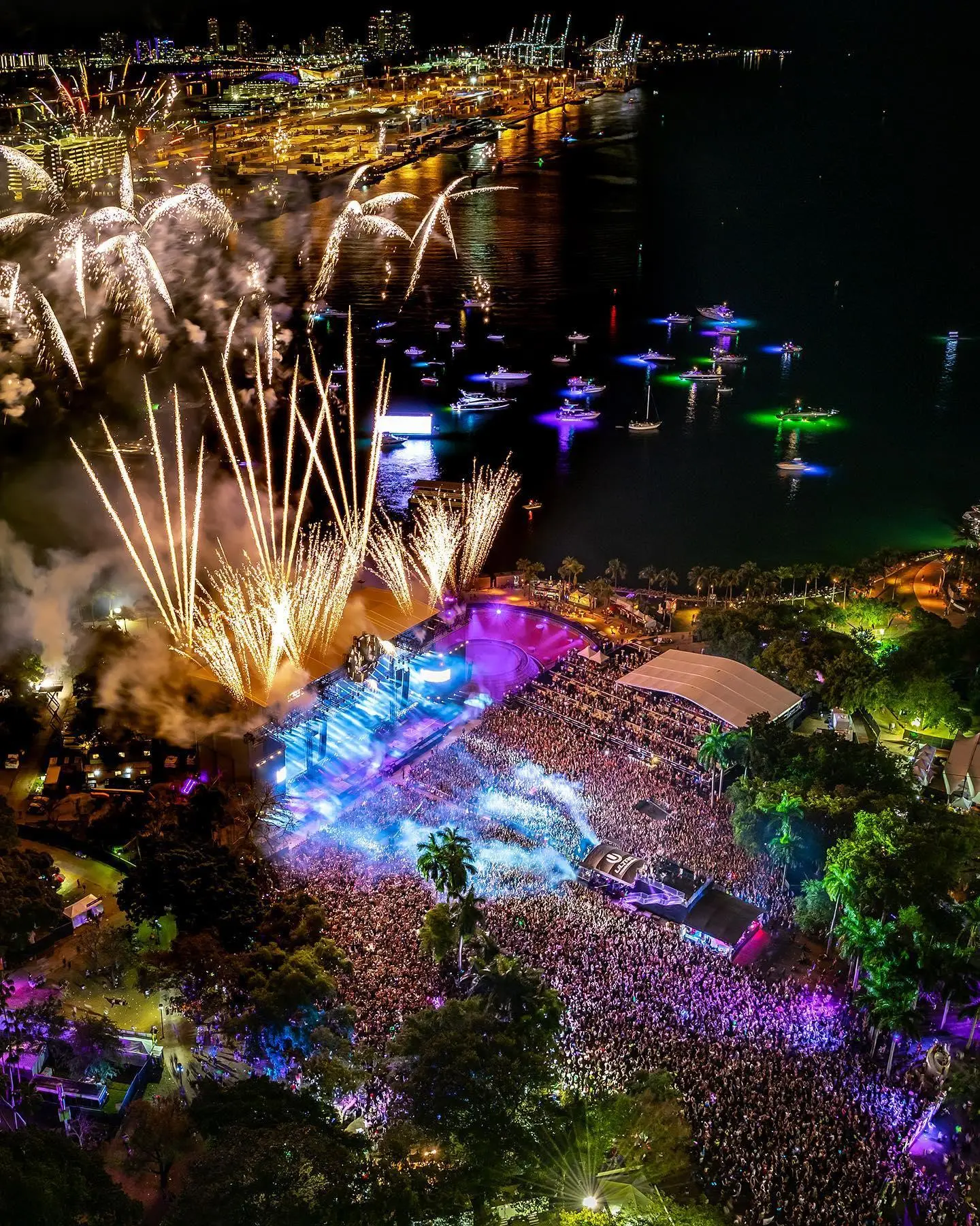 Aerial view of a music festival at night with fireworks and a large crowd